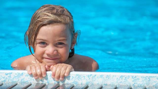 Niño en el bordillo de la piscina