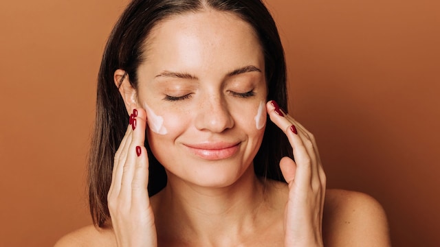 Rostro de mujer morena aplicándose crema en el rostro