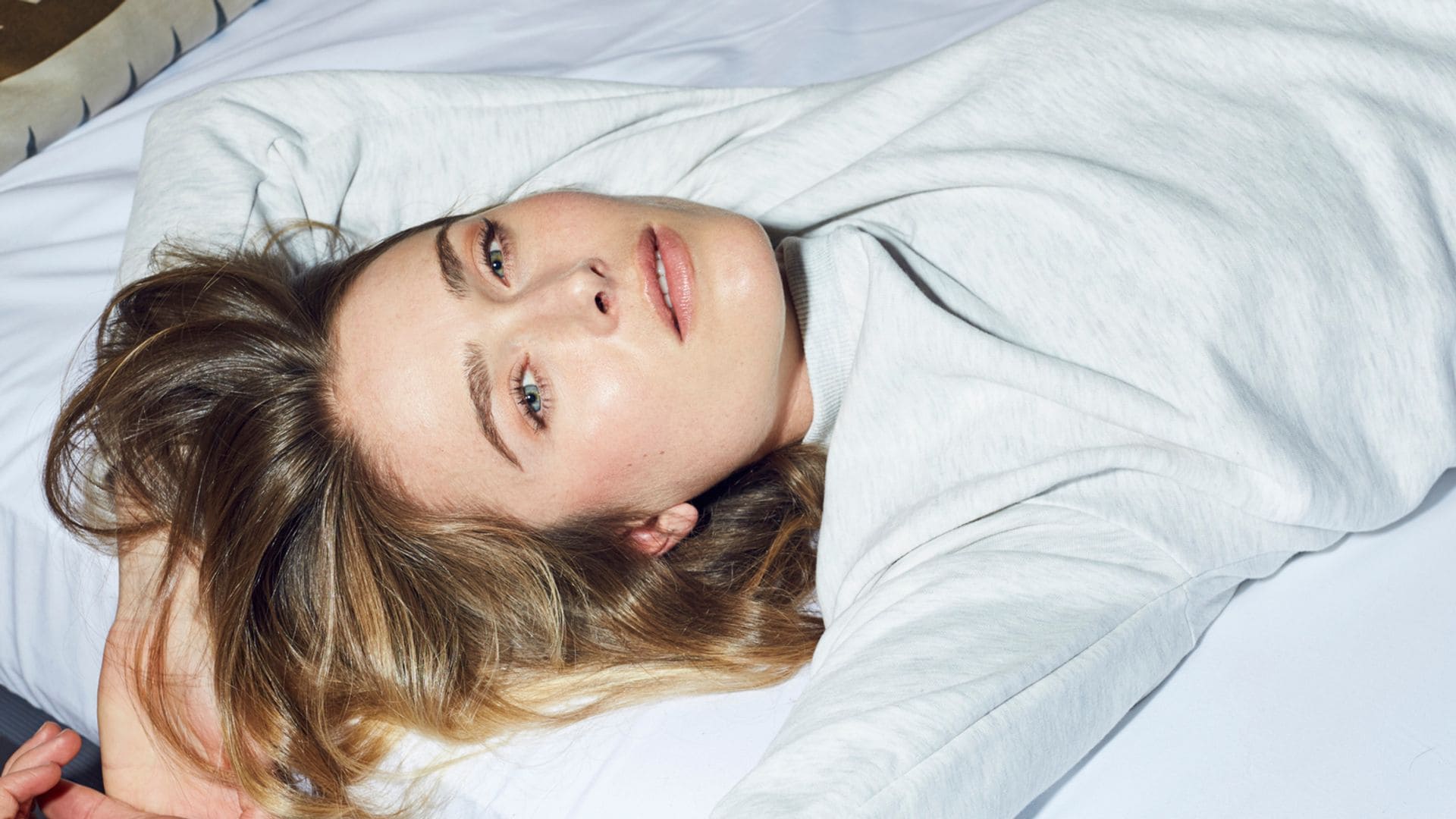 Mujer con camiseta blanca en una cama