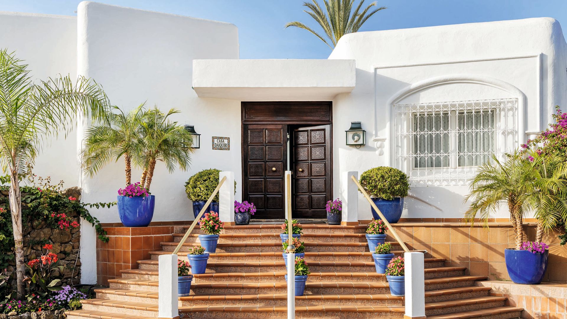 La entrada principal de la casa, que conserva el encanto arquitectónico de los años ochenta, definido por sus clásicas barandillas de hierro y líneas redondeadas.