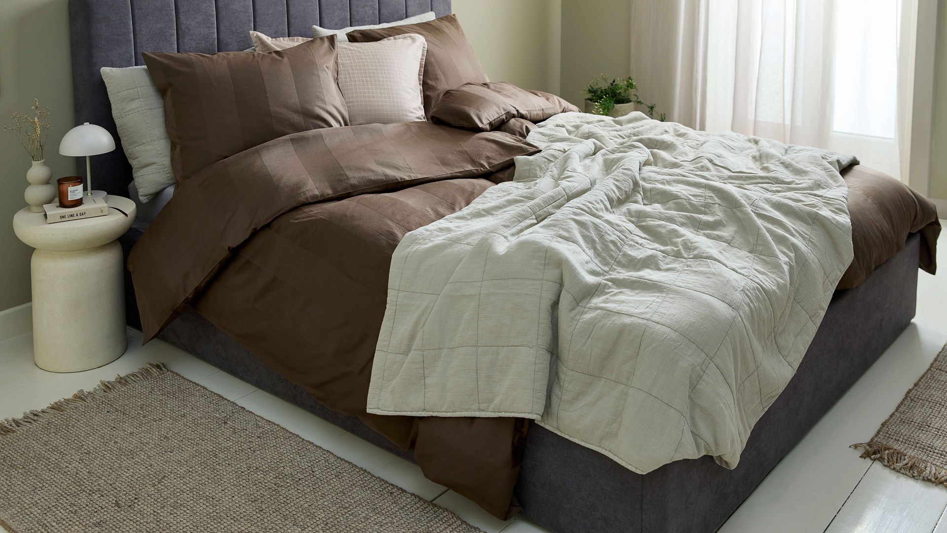 Dormitorio con cama con cabecero tapizado y canapé abatible, paredes en color verde, alfombra
