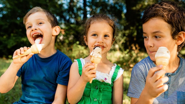Tres niños toman un helado en el parque