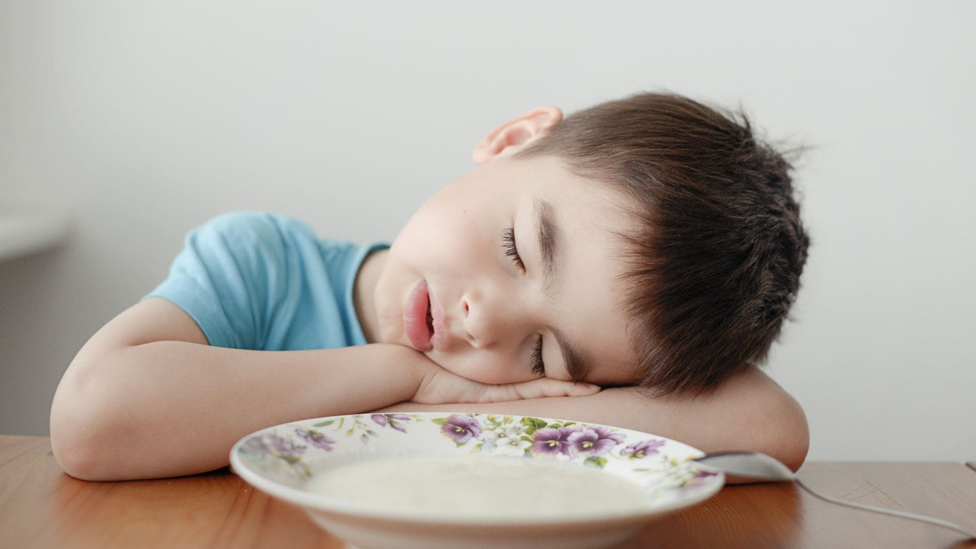 Niño pequeño dormido delante de un plato de comida