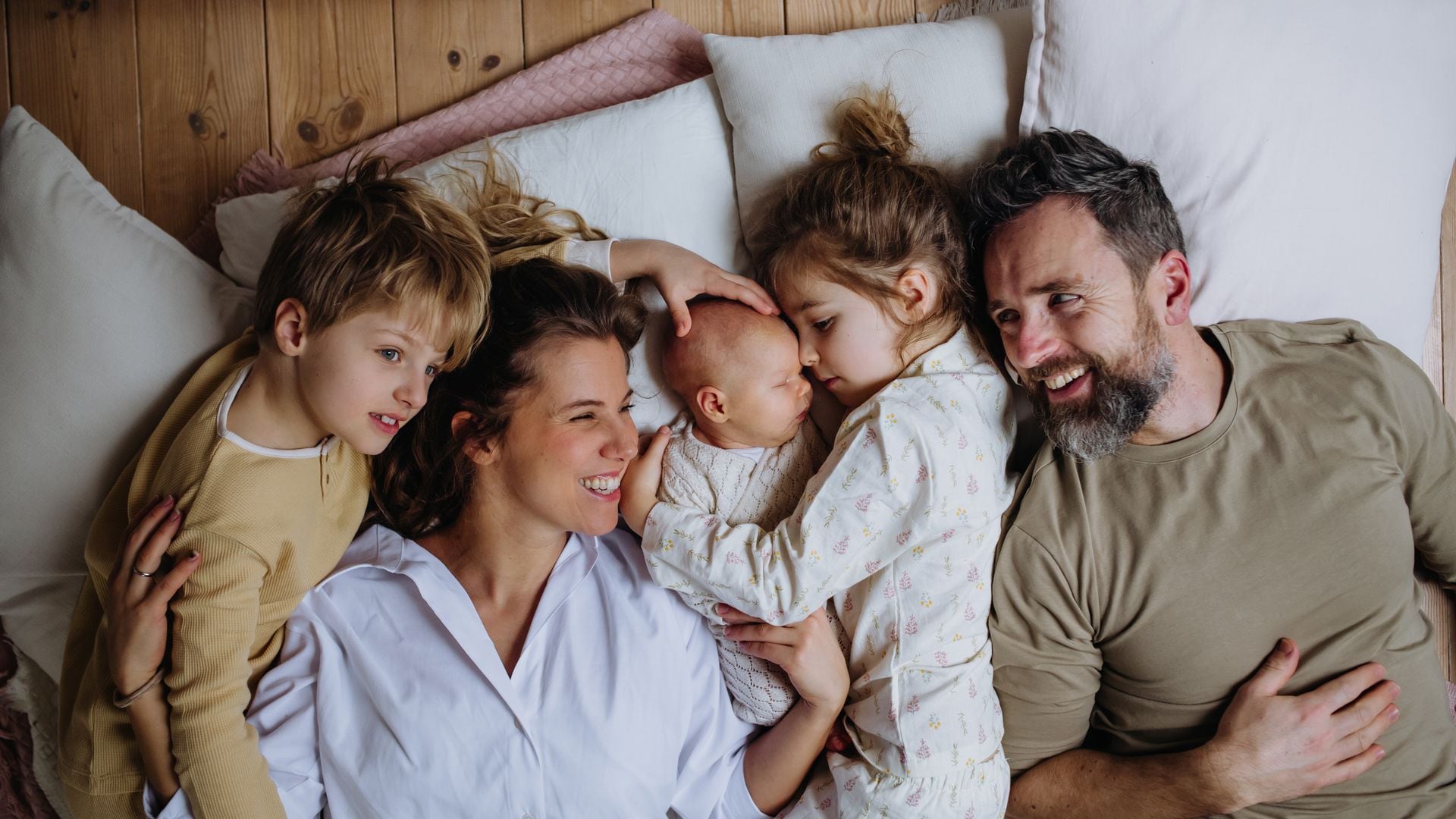 Familia con tres hijos tumbados juntos en la cama