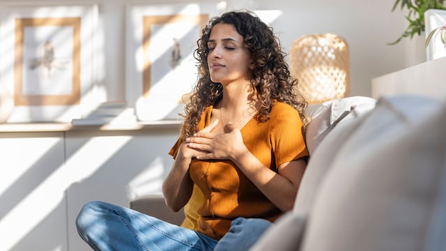 mujer joven meditando, sentada en el sofá