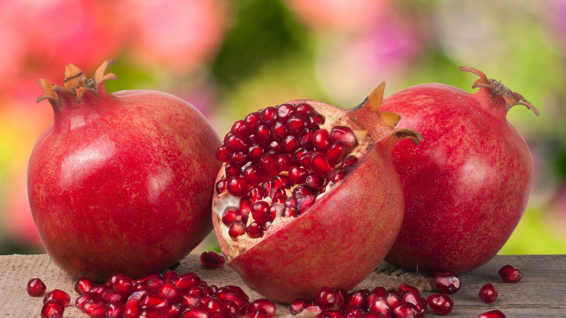 Dos granadas sin pelar y una a medio pelar con los granos delante.