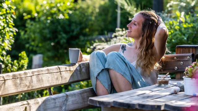 mujer joven relajada en una terraza, tomando un café