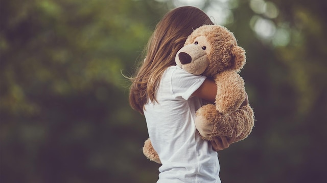 ni a abrazando a osito de peluche