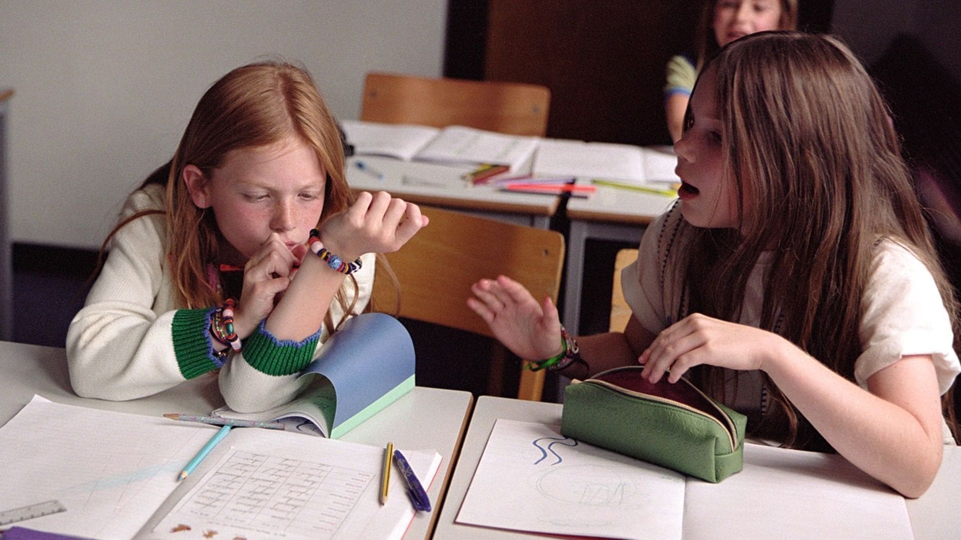 Niñas con estuches y cuadernos en sus pupitres en el colegio