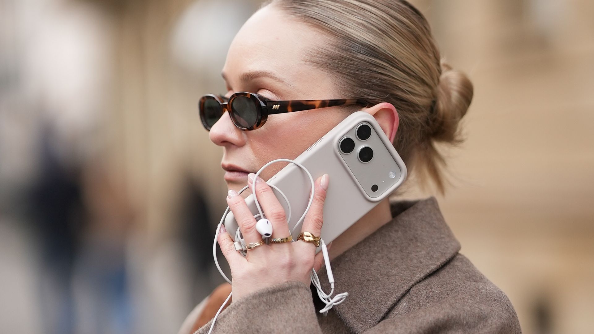 Sonia Sofianidou con abrigo marrón hablando por teléfono con un iphone 17