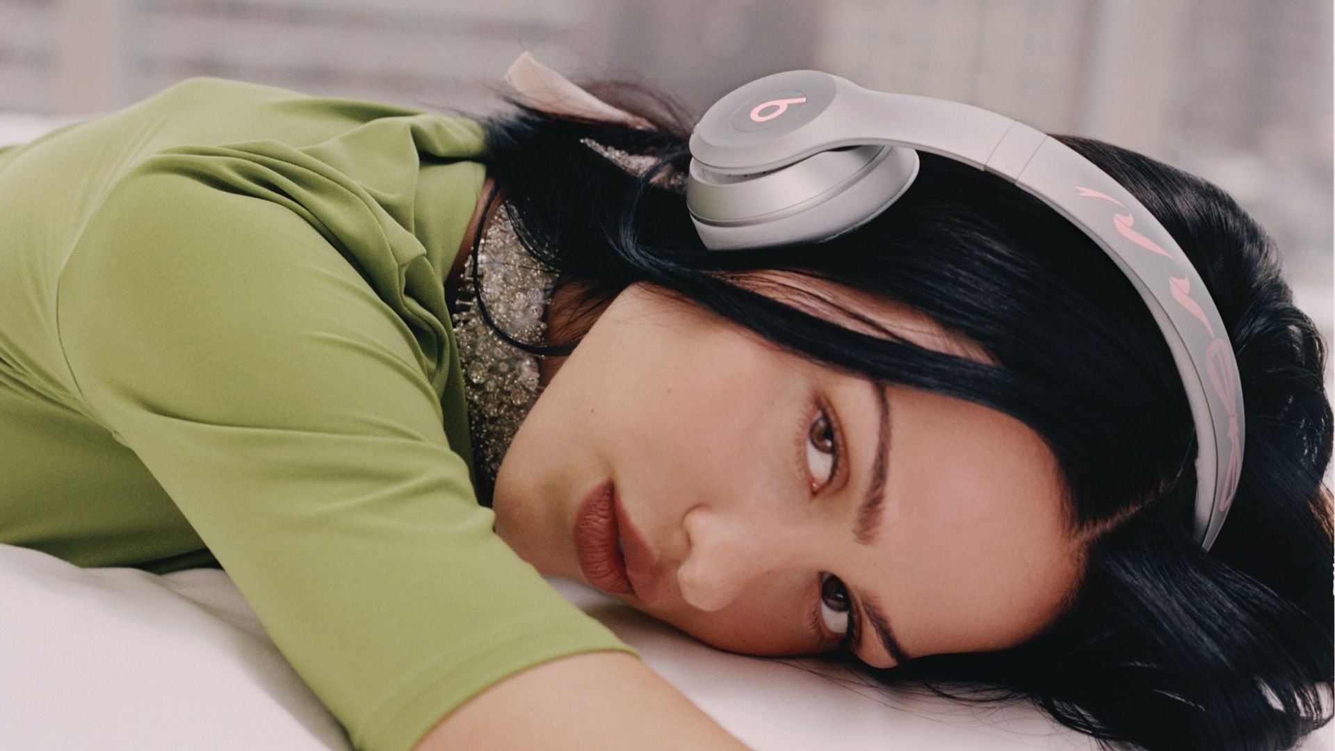 Mujer tumbada con auriculares de diadema de Beats puestos