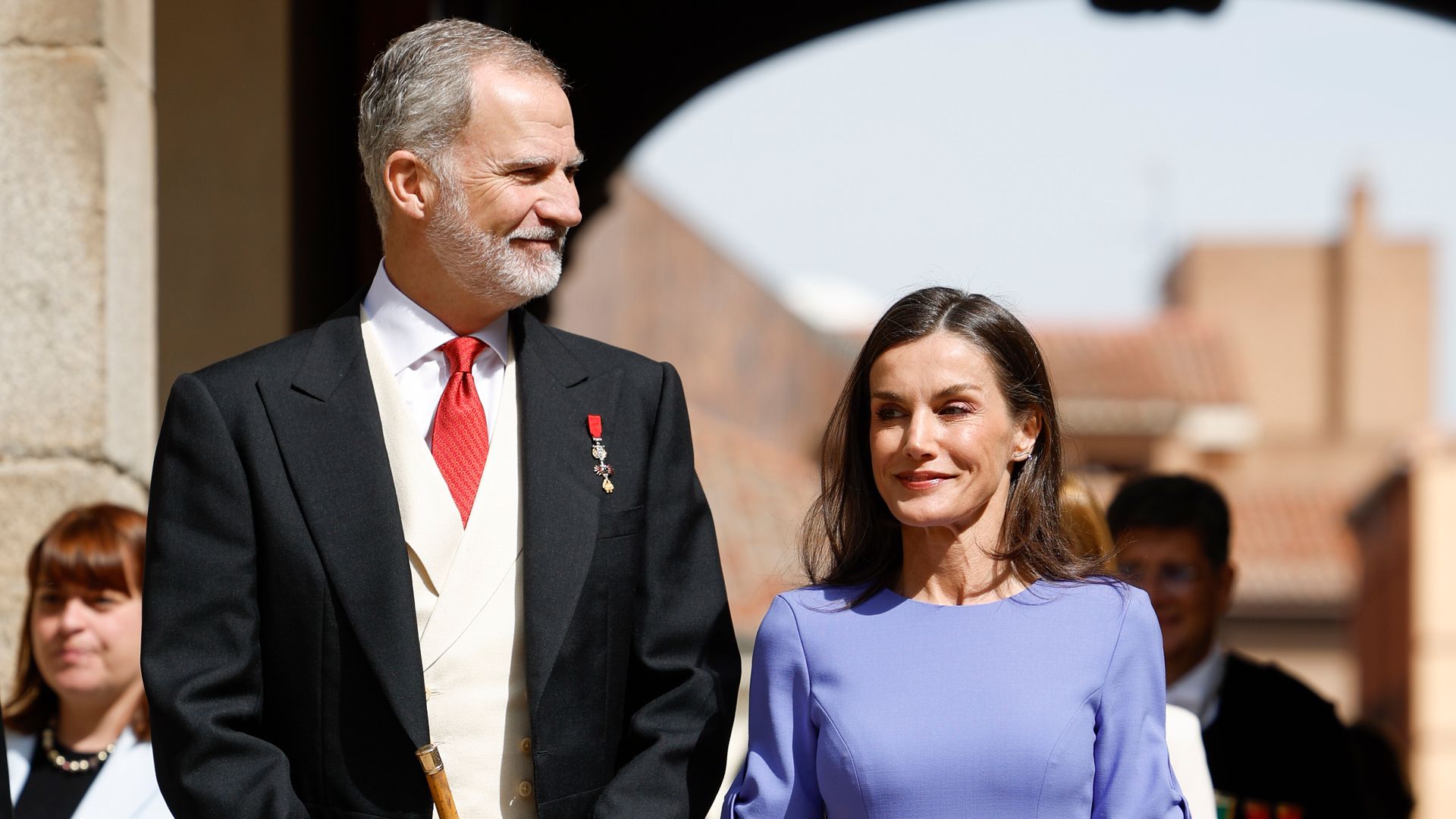La reina Letizia, radiante en Alcalá de Henares como la invitada perfecta de primavera: vestido violeta con lazos y llamativo bolso de flores 