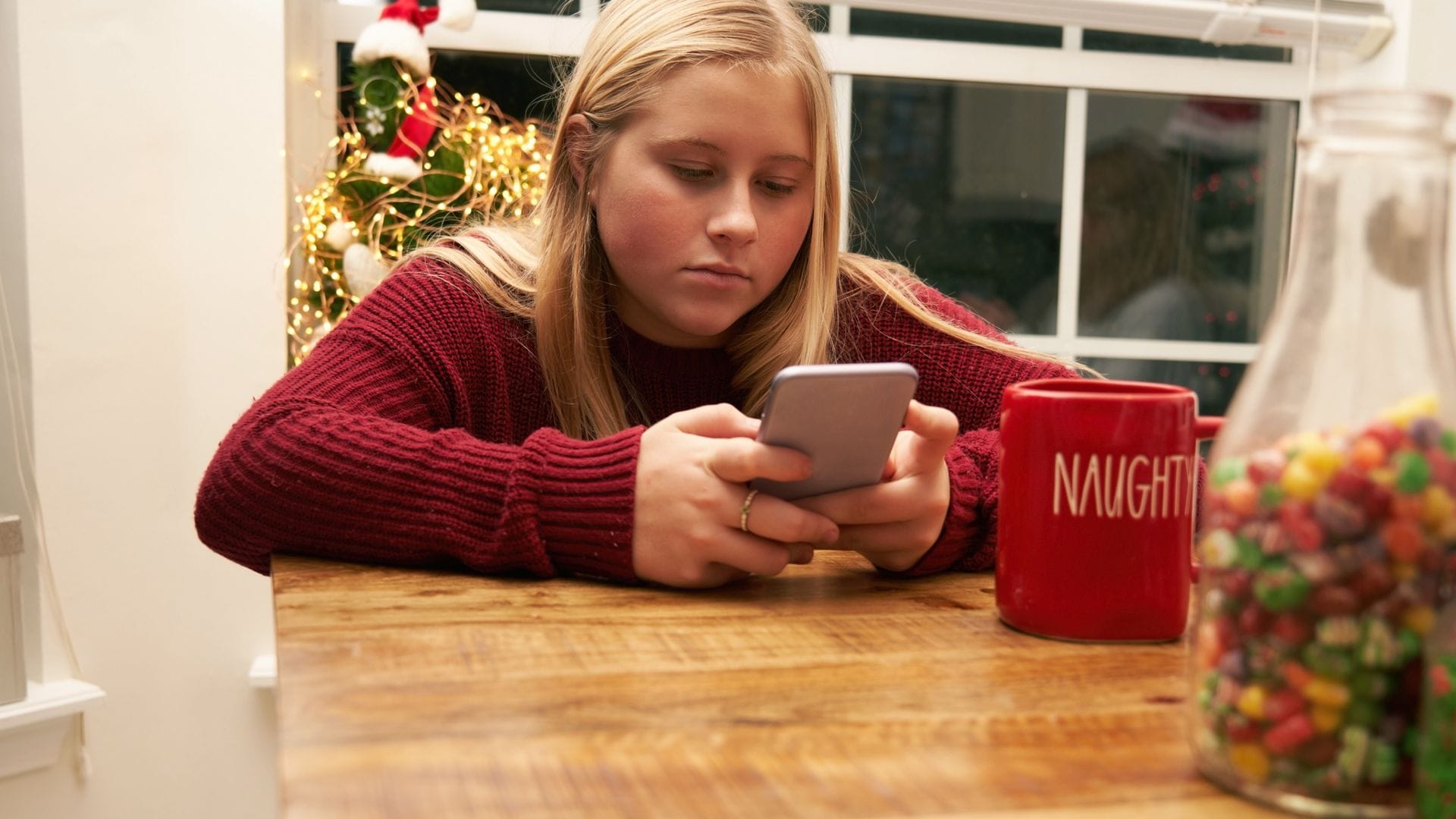 Adolescente aislada mirando el móvil en una comida navideña