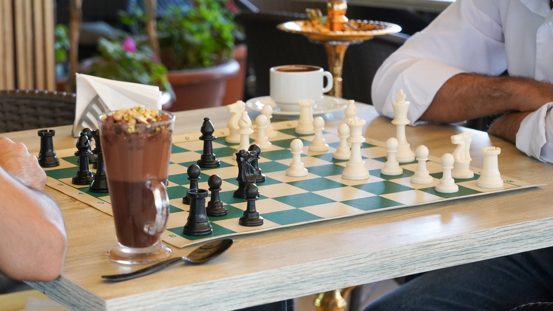 Partida de ajedrez con un postre de chocolate y un café al lado