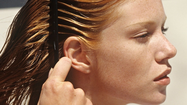 Young woman combing her hair, outdoors