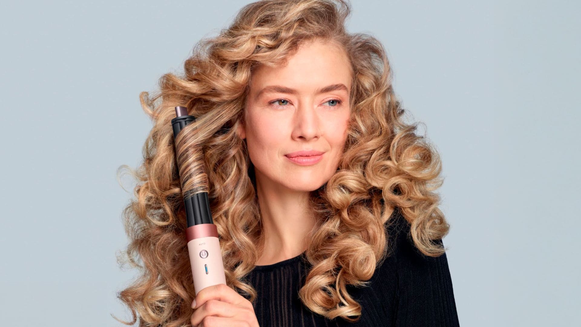 Mujer con pelo rubio haciéndose ondas con el moldeador Dyson Airwrap i.d.