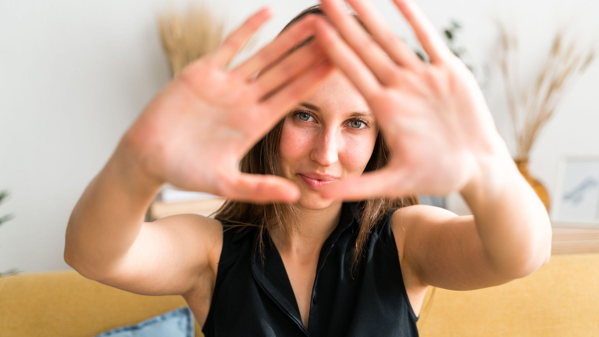 Una mujer escondida con sus manos delante de la cámara