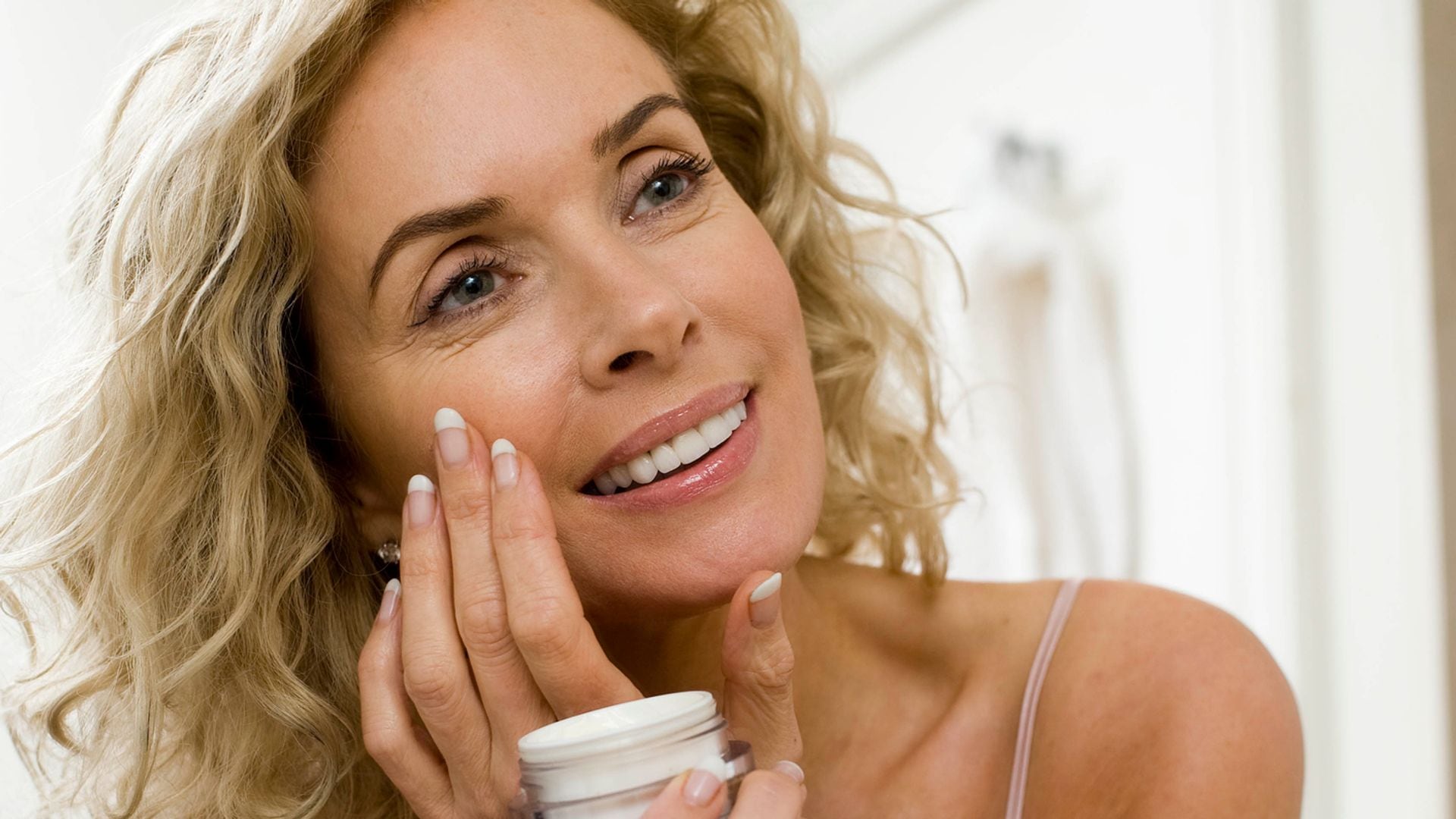 Rostro de mujer madura aplicándose crema hidratante