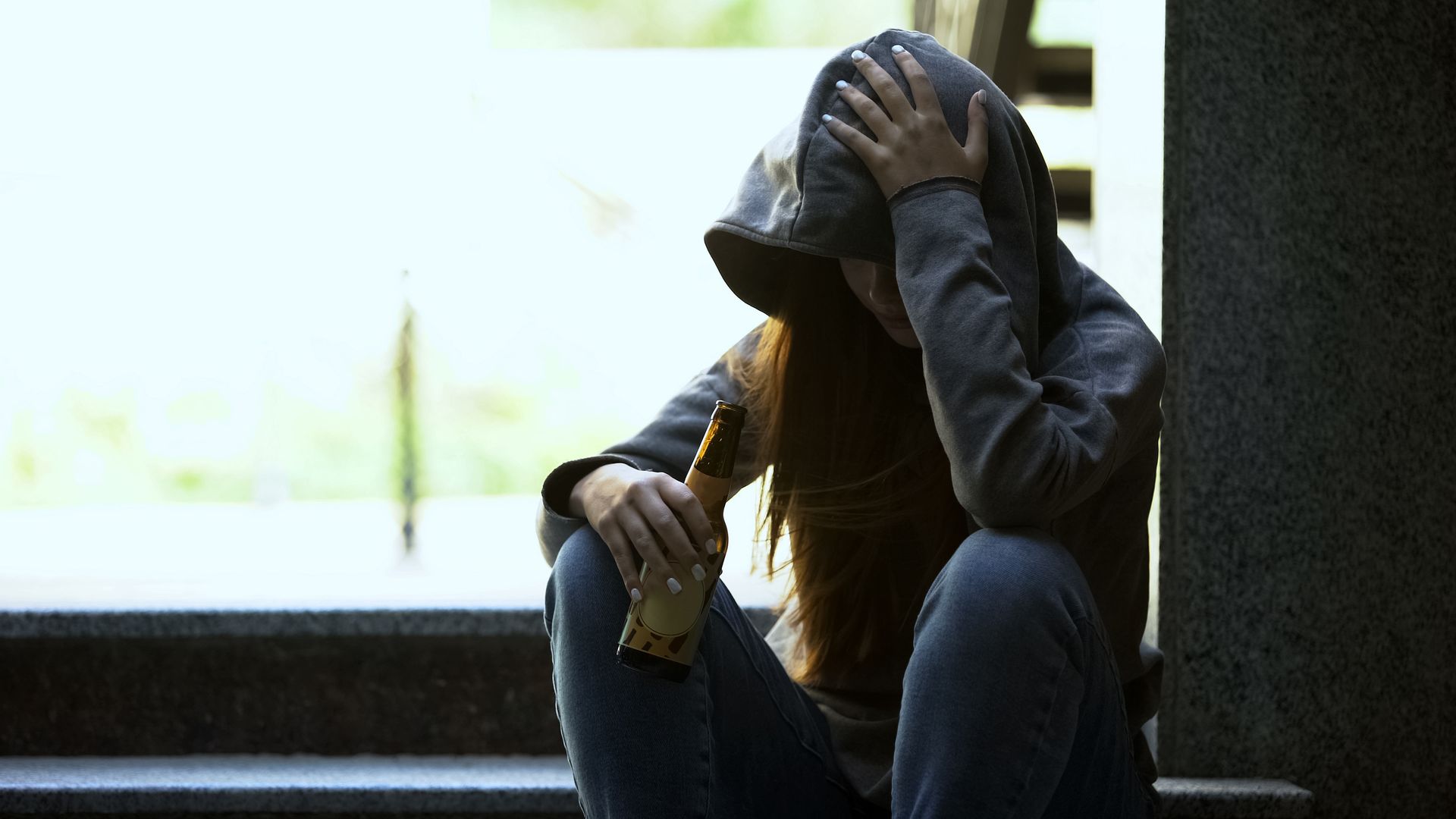 Chica adolescente con altas capacidades con una botella de alcohol en la mano