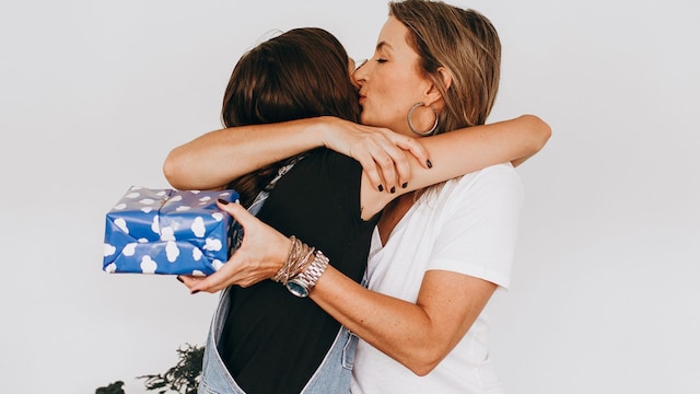 Chica adolescente dándole un regalo a su madre por el Día de la Madre con un abrazo