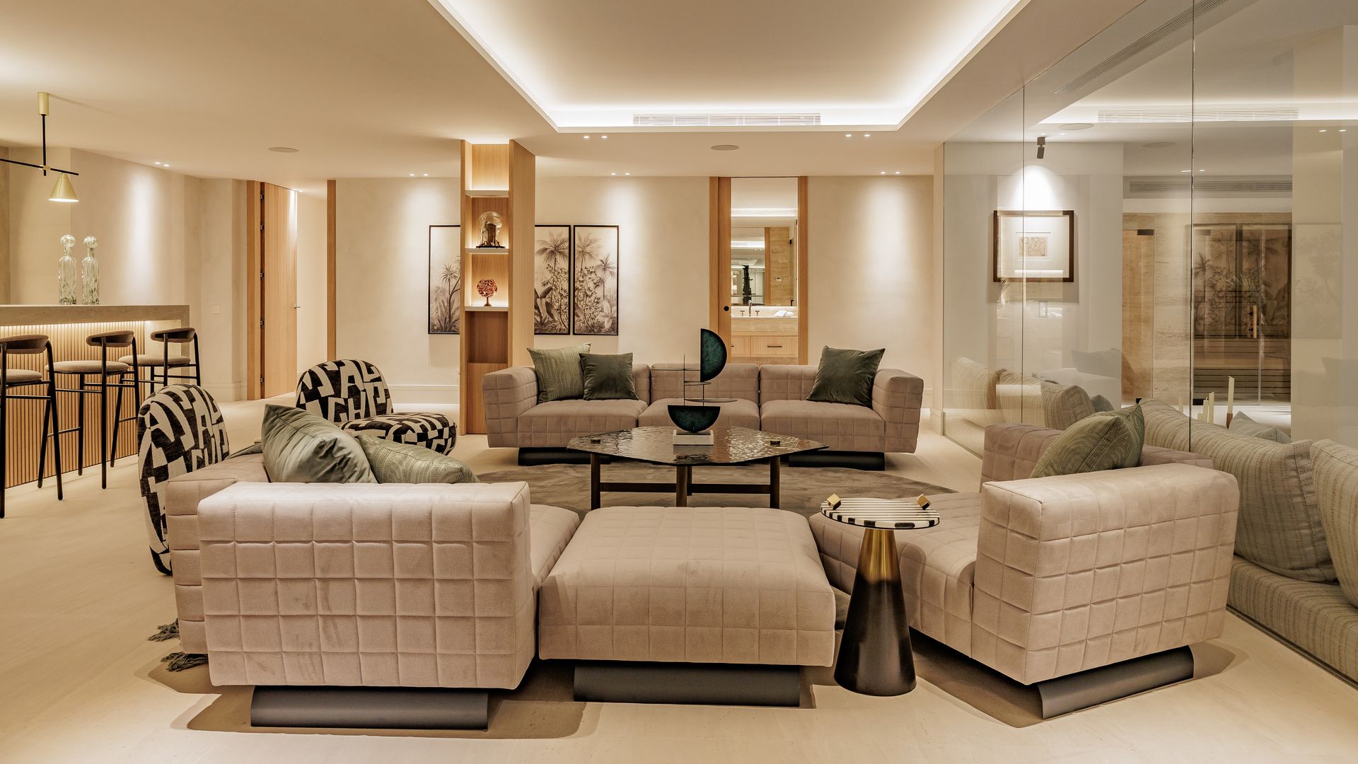 Salón con pared de espejo, iluminación integrada en el techo, sofás con asiento bajo y pufs, barra de bar, estantería de madera en columna