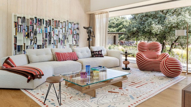 Salón con alfombra blanca con motivos, butaca de rayas rojas con puf a juego, sofá blanco y estantería llena de libros