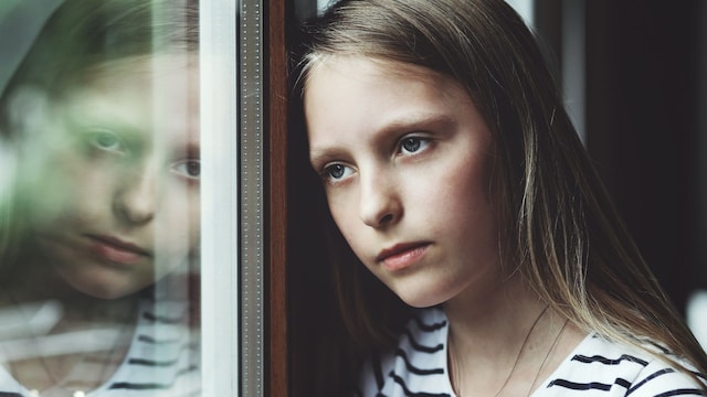 Adolescente triste mirando por la ventana