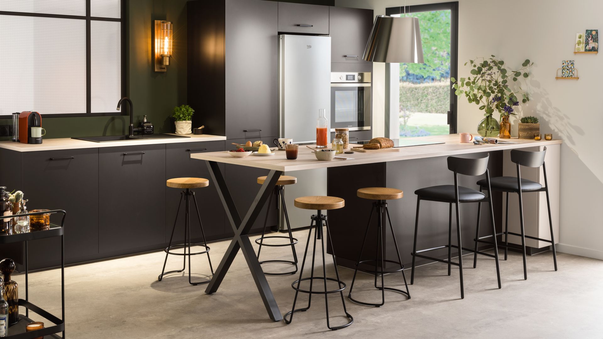 Cocina abierta con isla con taburetes, muebles negros, campana lámpara, focos techo