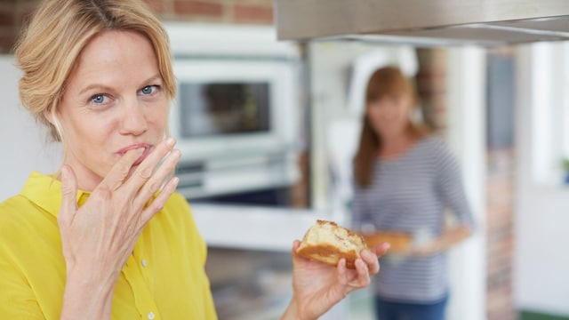 Mujer comiendo dulce en la cocina 