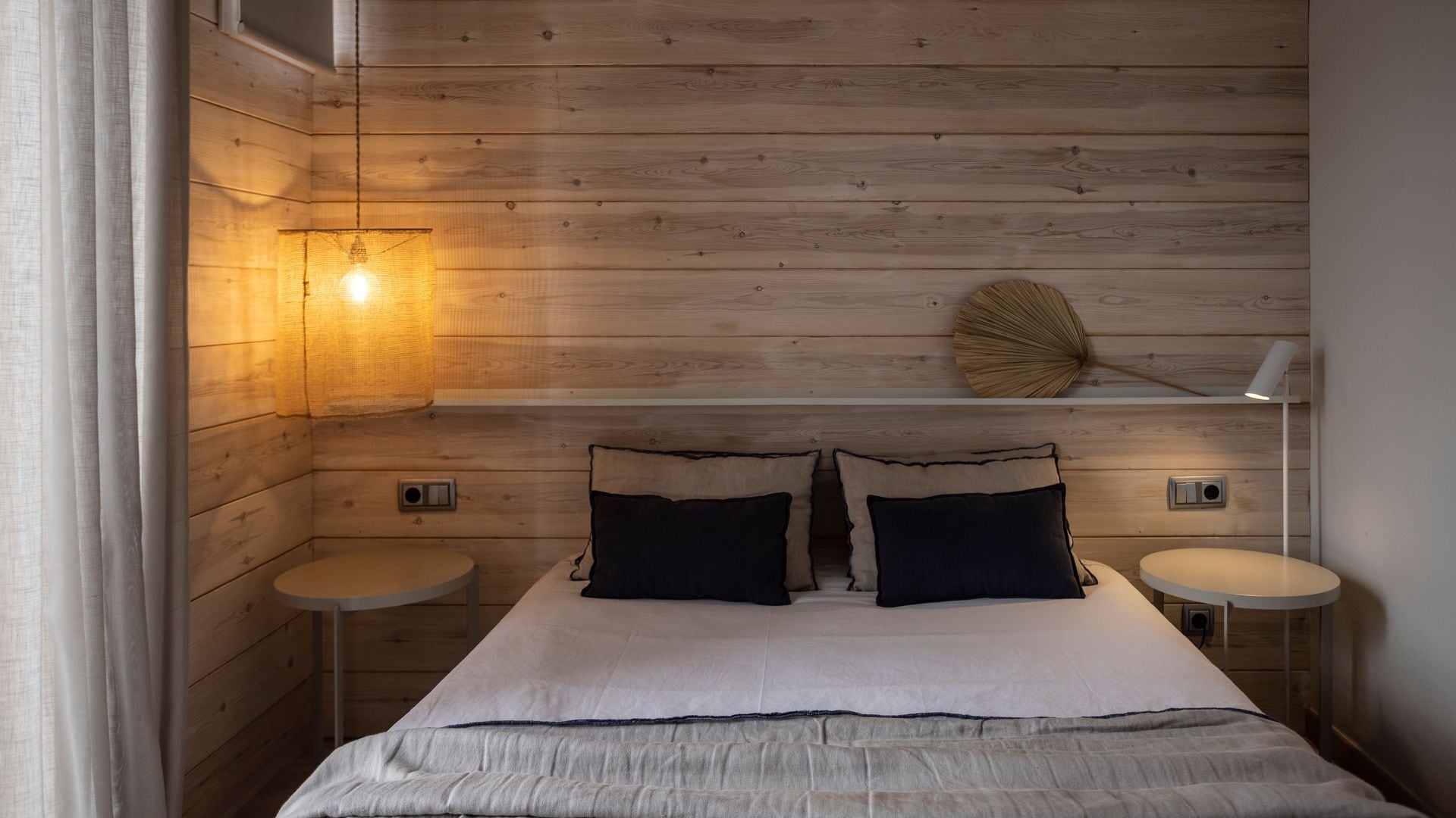 Dormitorio con paredes de madera, balda, mesitas de noche, lámpara de techo