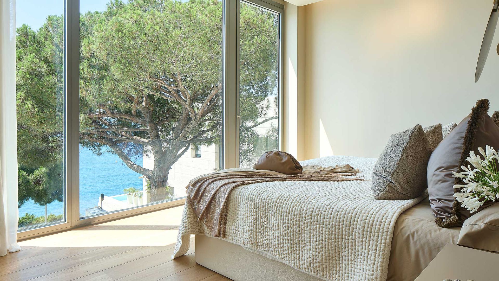 Dormitorio con cama que mira al exterior a través de un gran ventanal