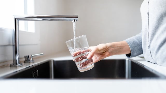Una mujer llenando un vaso de agua