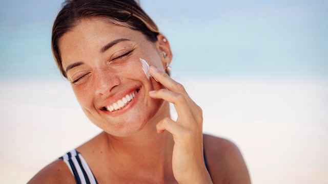 Mujer aplicándose protector solar en la playa