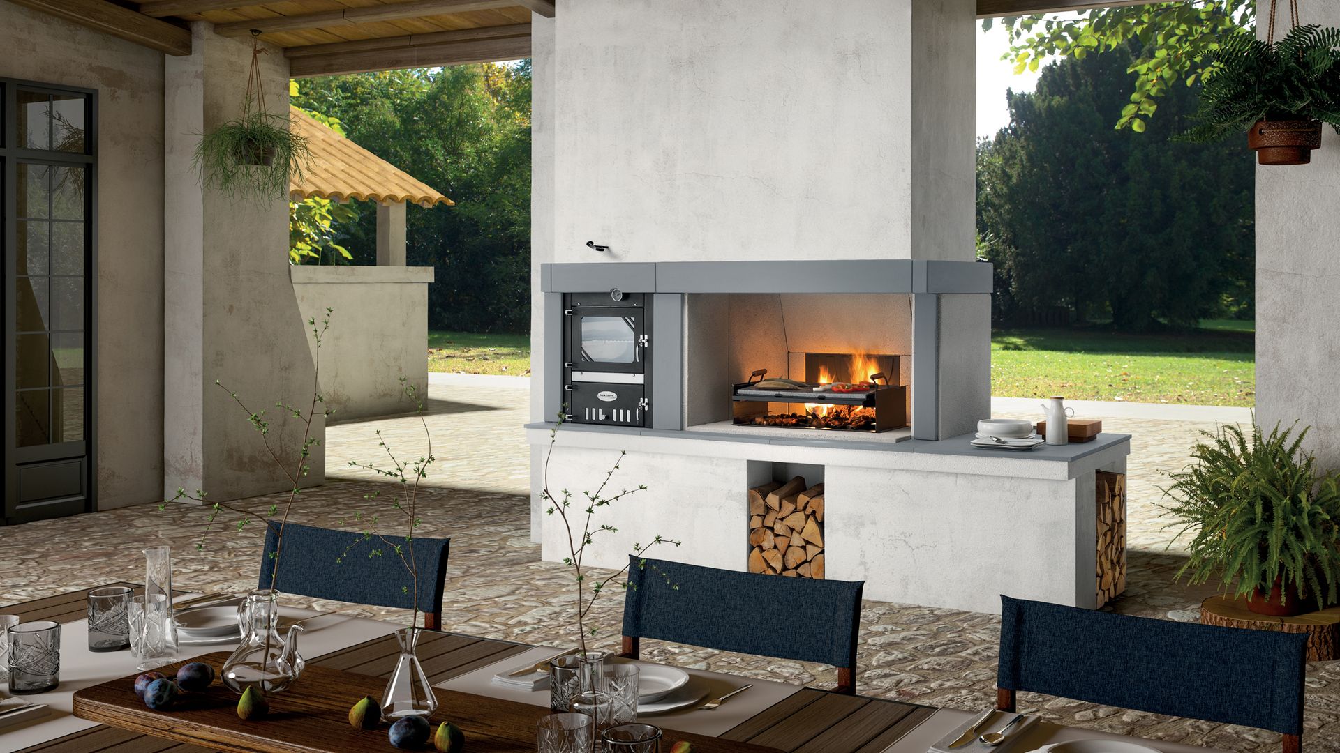 Cocina exterior con barbacoa y horno, mesa de comedor montada con manteles individuales