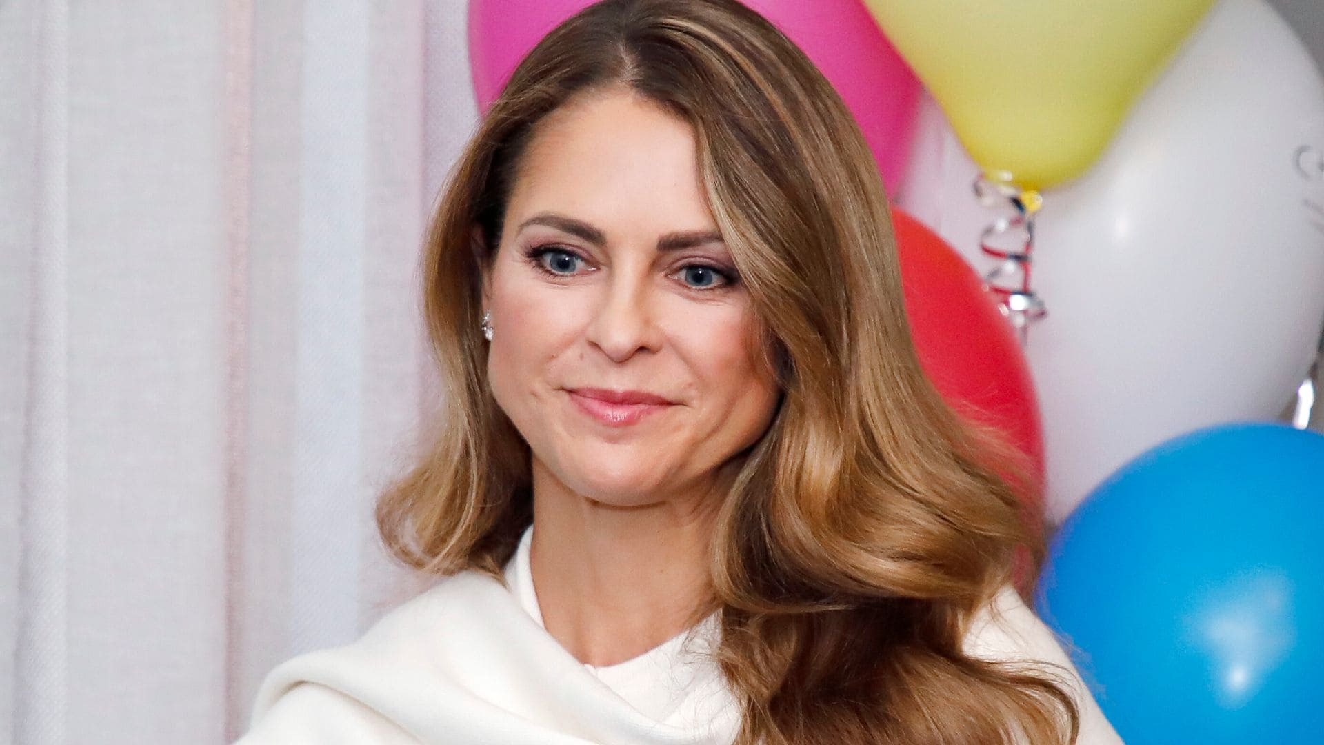 La princesa Magdalena de Suecia en Estocolmo con jersey blanco con bufanda a juego y melena ondulada