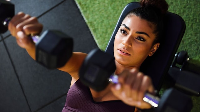 Mujer entrenando con pesas en banco de gimnasio