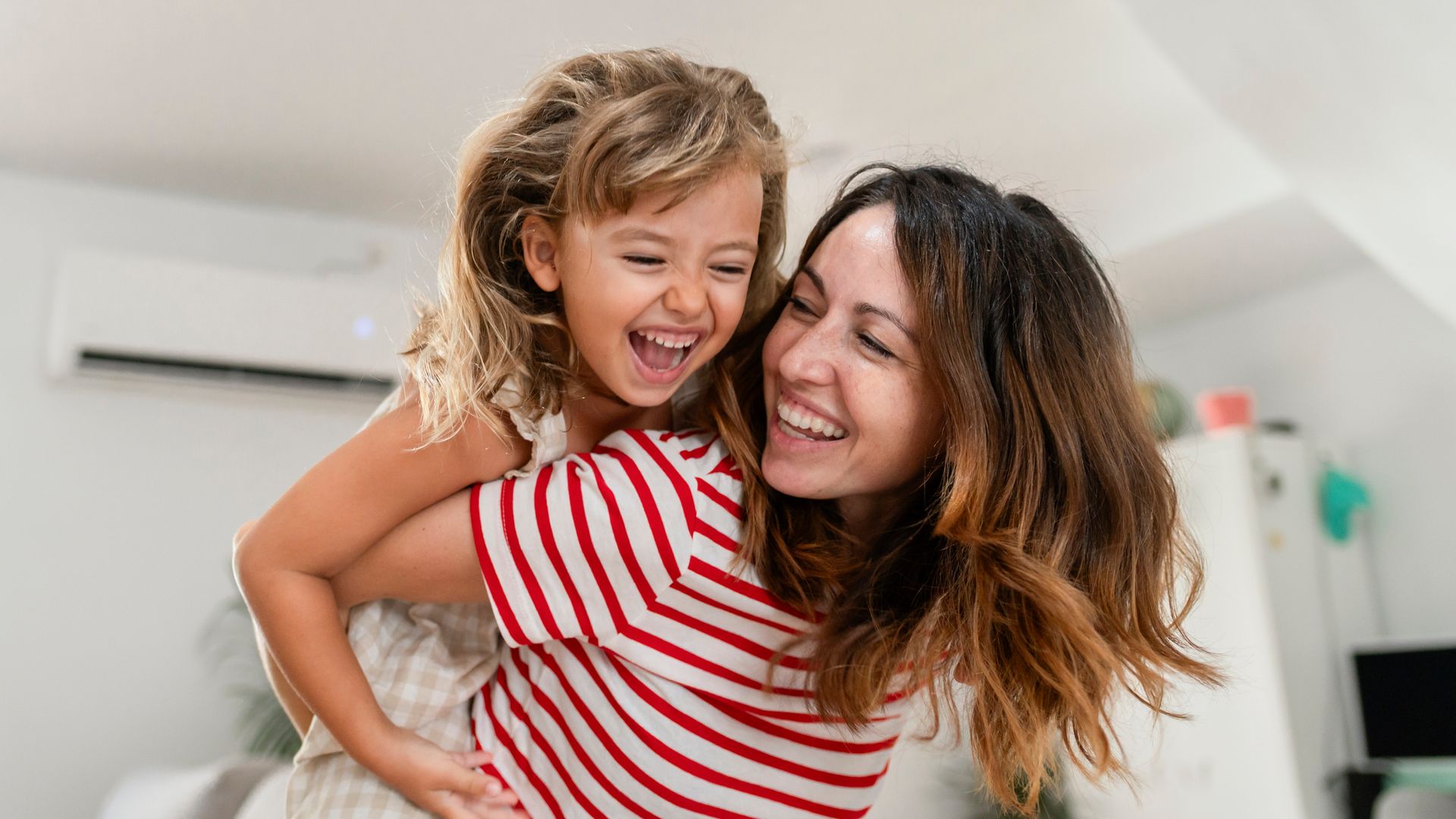 Madre e hija sonriendo y jugando en su casa