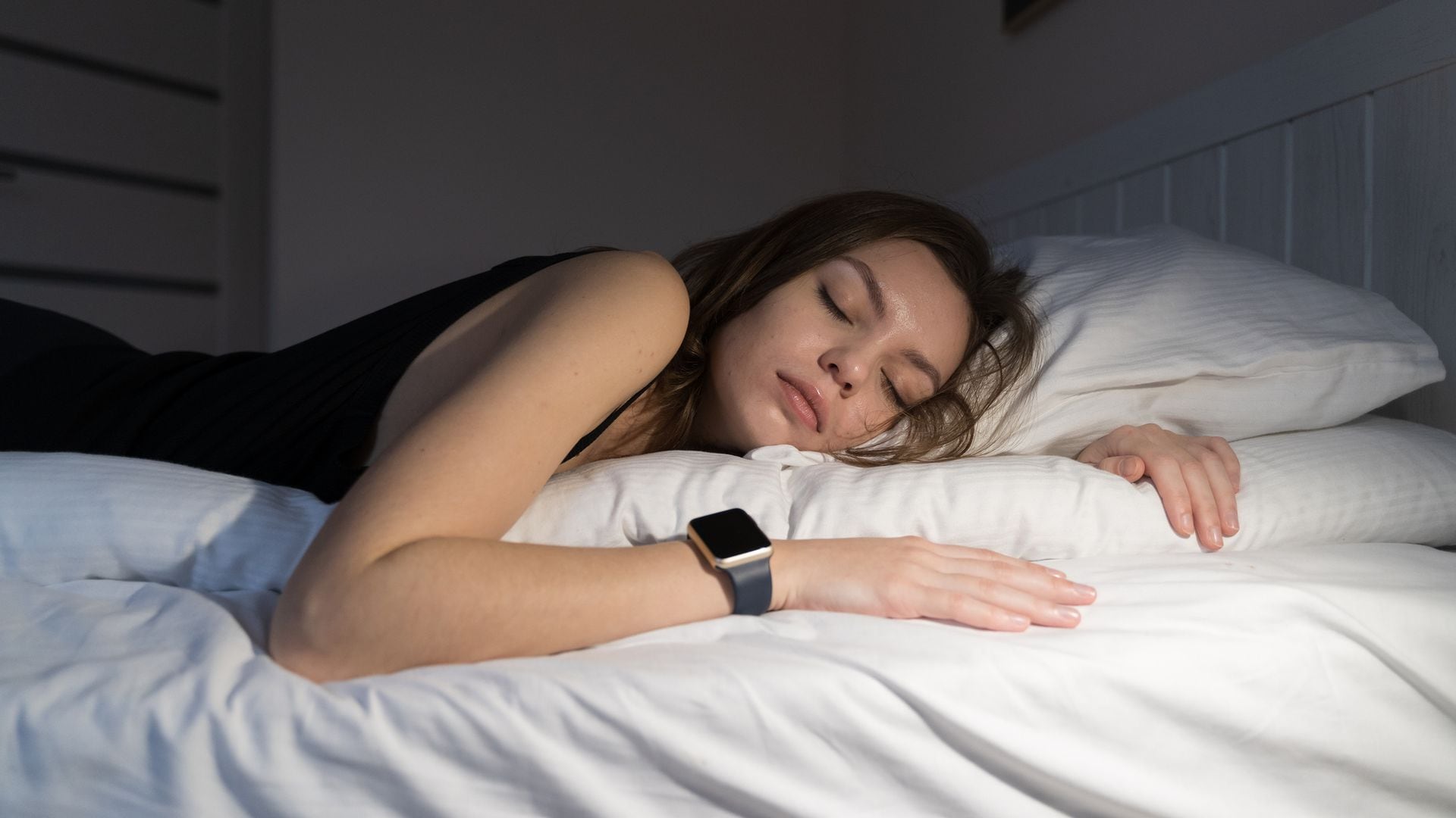 mujer durmiendo en la cama con un reloj inteligente