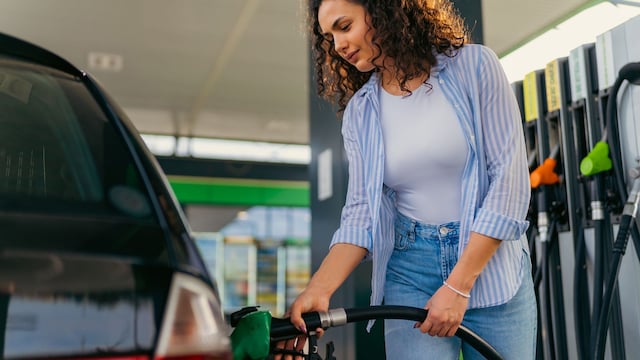 Una mujer joven reposta su vehículo en una gasolinera 