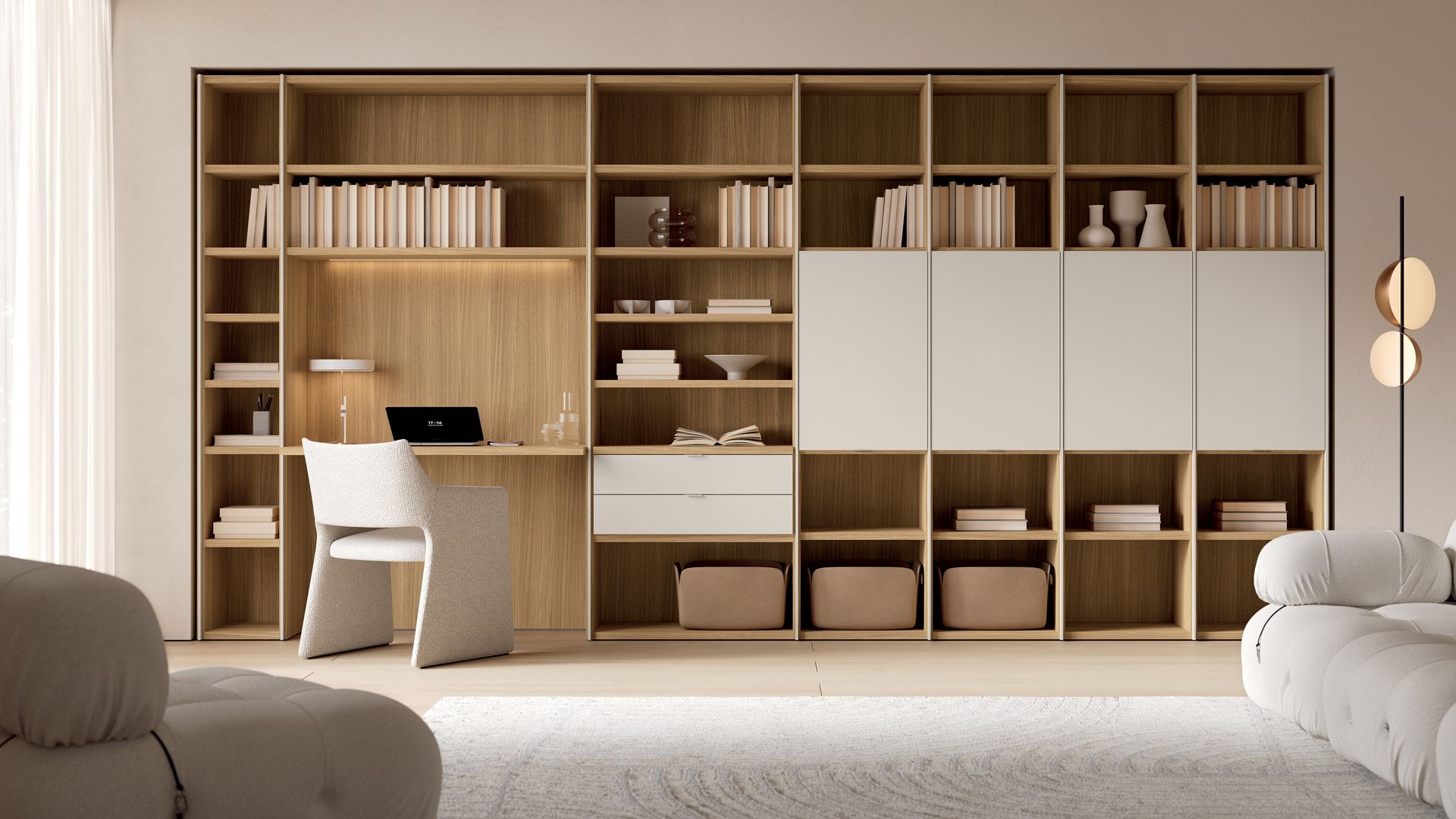 Librería de pared a pared con zonas cerradas y hueco de escritorio, alfombra y sofá blanco, butaca blanca