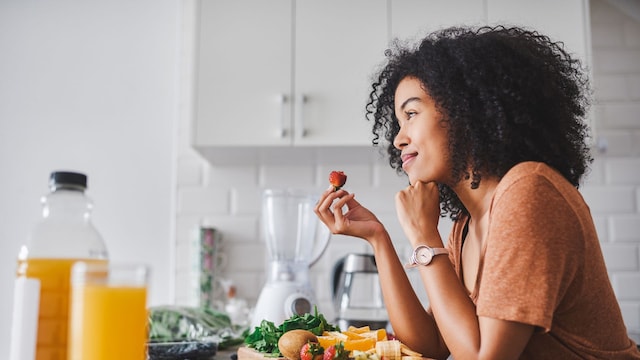 mujer comiendo fruta en la cocina