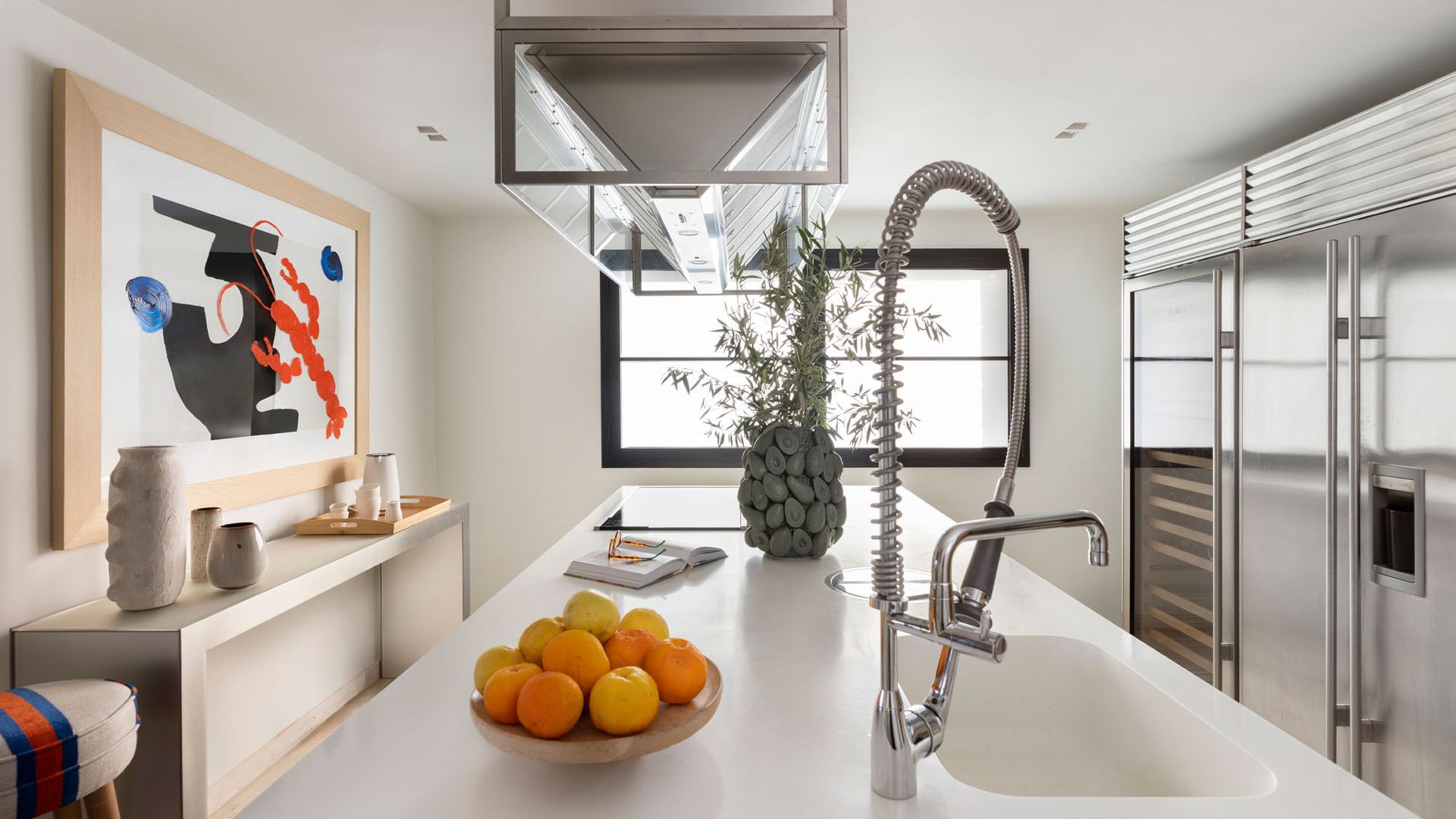 Cocina con muebles blancos, cuadro, armarios blancos con módulo abierto en madera oscura, campana decorativa