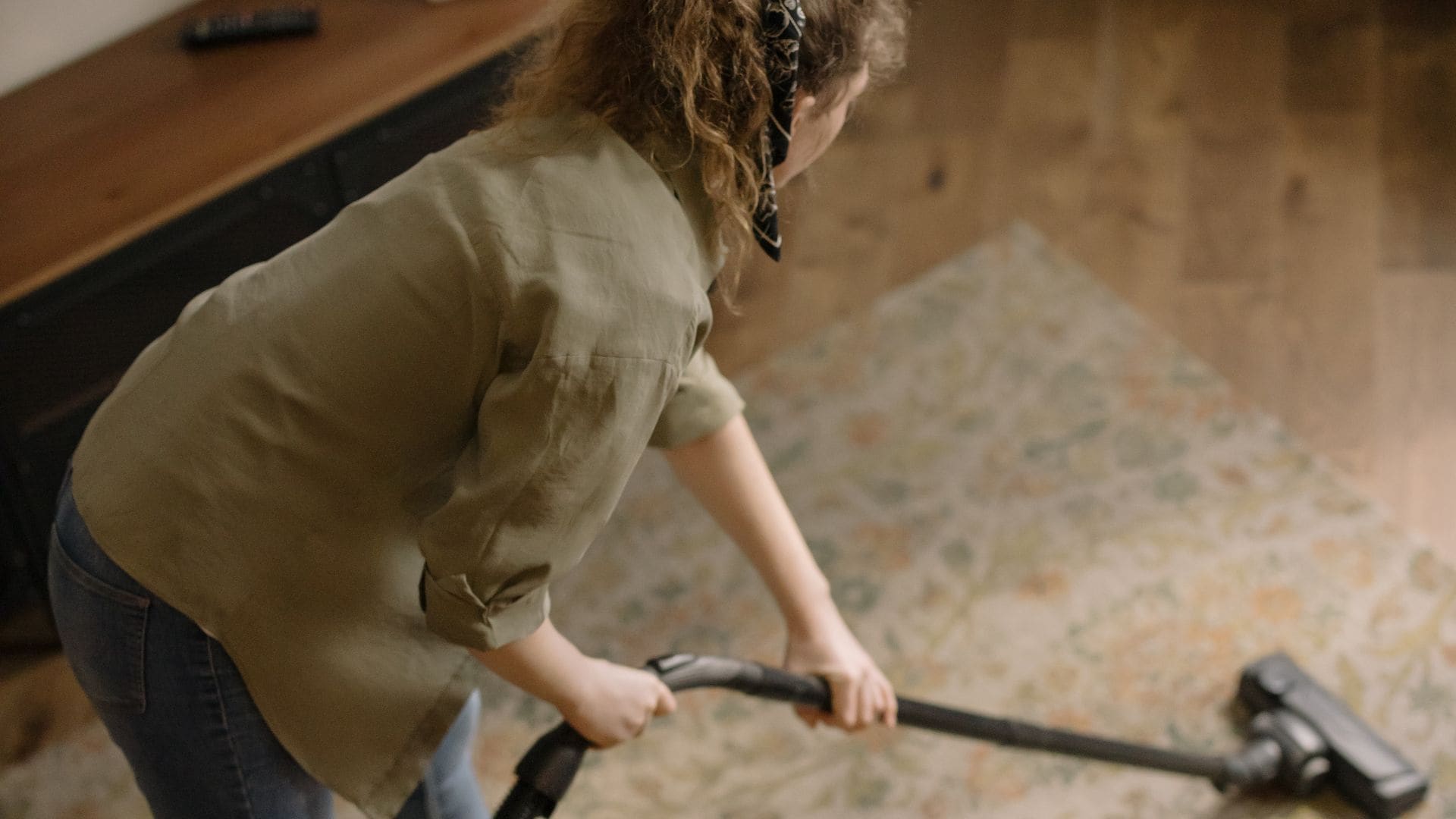 Mujer limpiando con una alfombra con el aspirador.