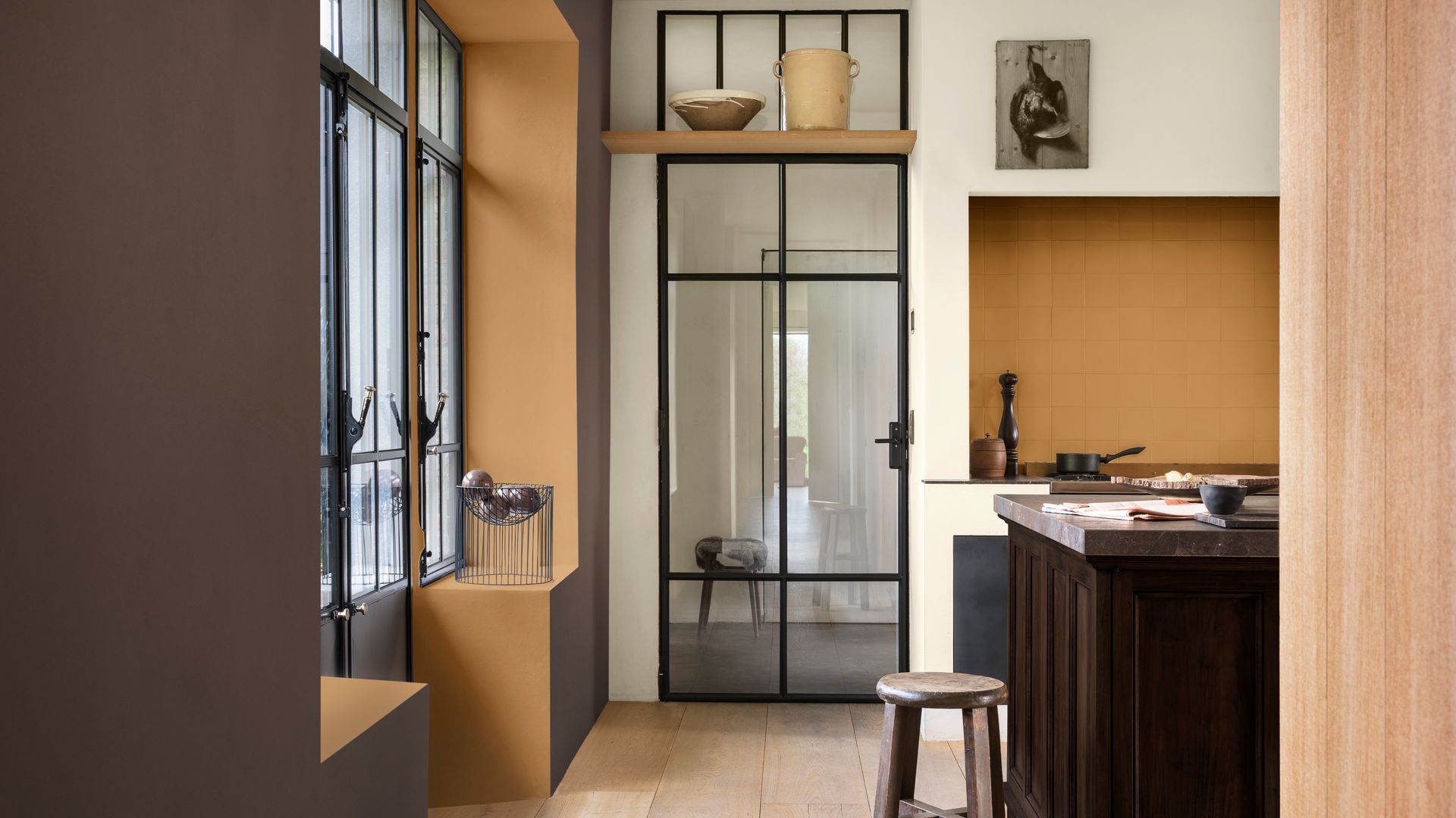 Cocina con salida el exterior con paredes en marrón y chocolate, suelo de madera, puerta de cristal 