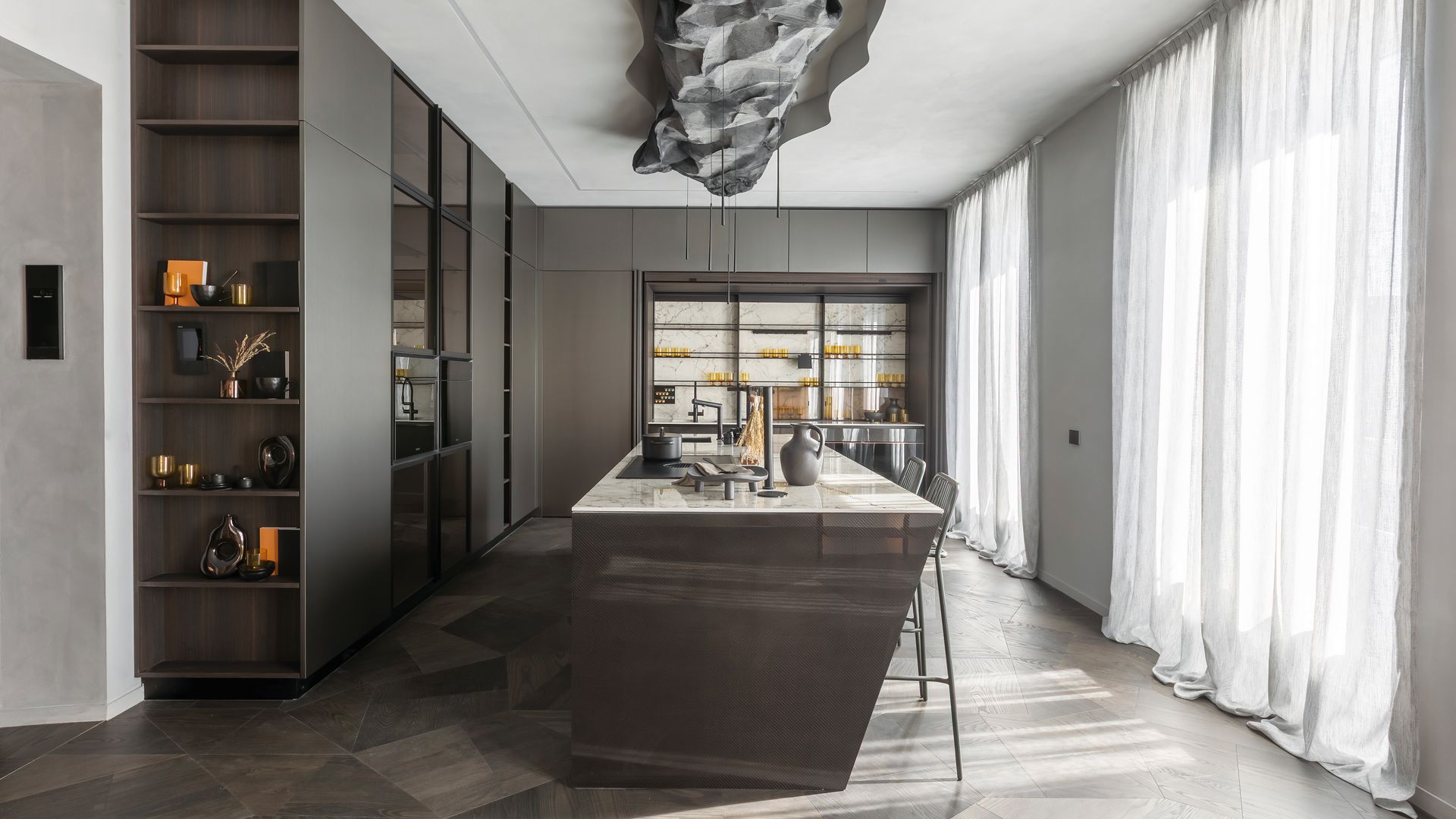 Cocina de Casa Decor 2025 de Doimo Cucine con isla central, armarios, estanterías, lámpara de techo, cortinas blancas