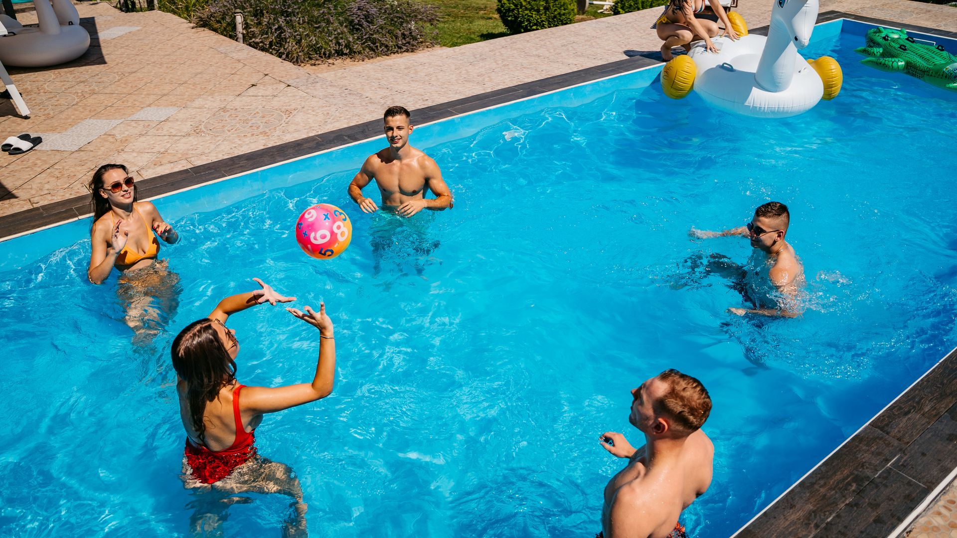 Amigos jugando voleibol en la piscina