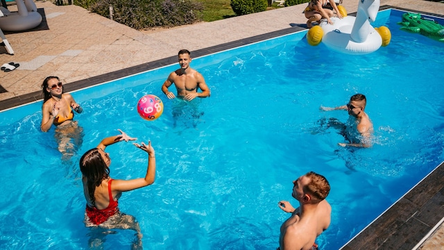 Amigos jugando voleibol en la piscina