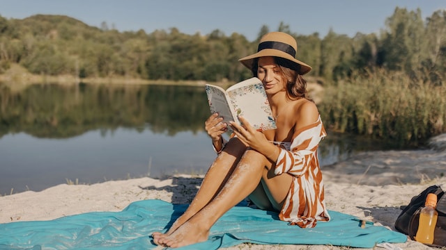 Mujer leyendo un libro sobre la arena 
