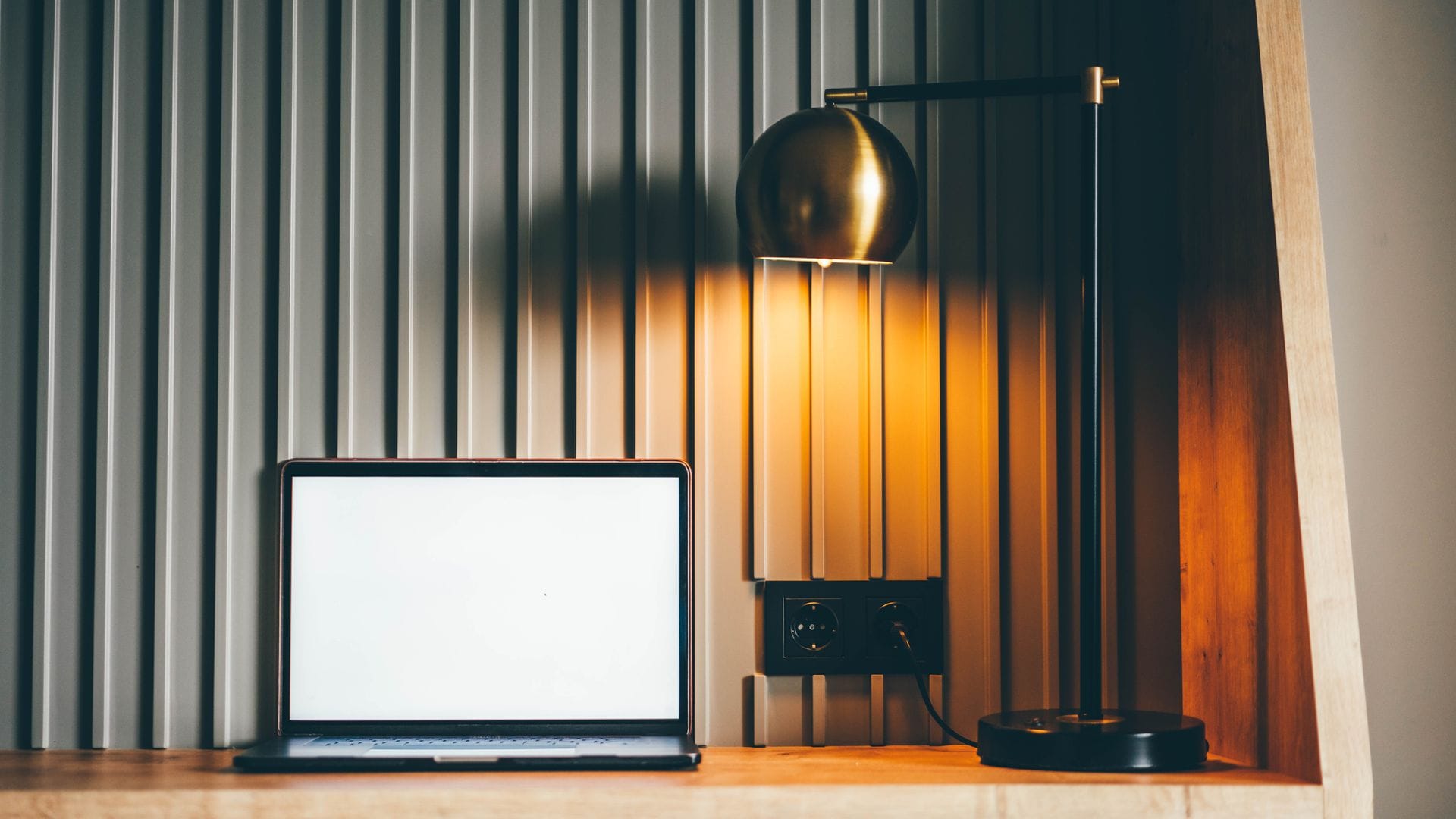 Escritorio de madera con ordenador portátil y lámpara de mesa.