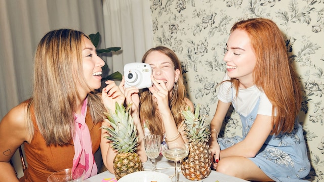 grupo de amigas en una divertida cena, con una cámara de fotos